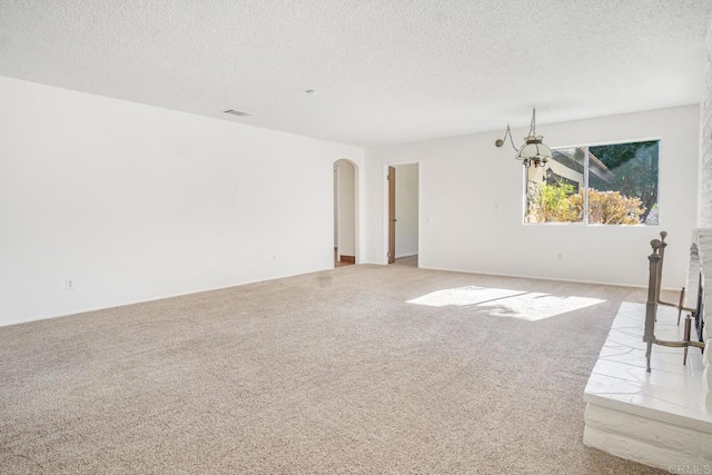 carpeted spare room with a textured ceiling and a notable chandelier