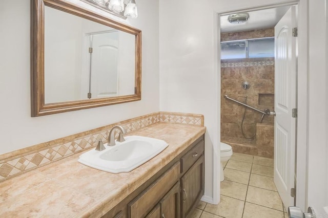 bathroom featuring vanity, tiled shower, tile patterned floors, and toilet