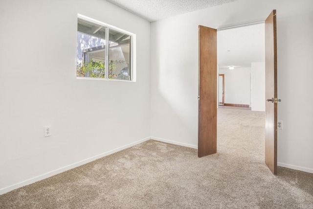 carpeted empty room featuring a textured ceiling