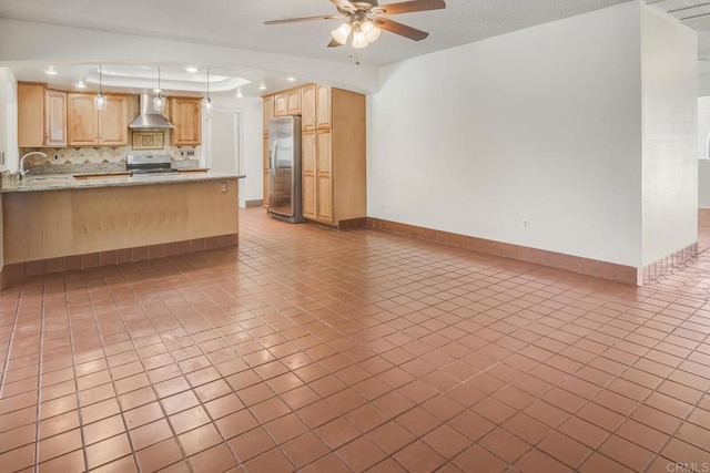 kitchen featuring hanging light fixtures, stainless steel appliances, light stone counters, kitchen peninsula, and wall chimney exhaust hood