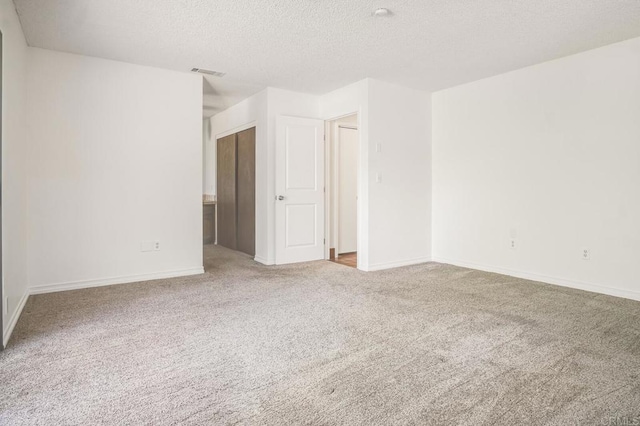 carpeted empty room featuring a textured ceiling