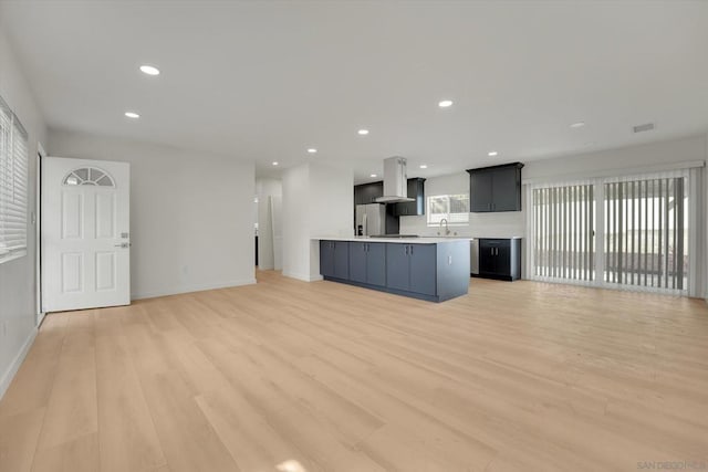 unfurnished living room with a healthy amount of sunlight, sink, and light hardwood / wood-style flooring