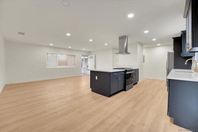 kitchen featuring stainless steel refrigerator, sink, gas stove, wall chimney range hood, and light hardwood / wood-style flooring