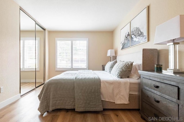 bedroom with a closet, light hardwood / wood-style floors, and multiple windows