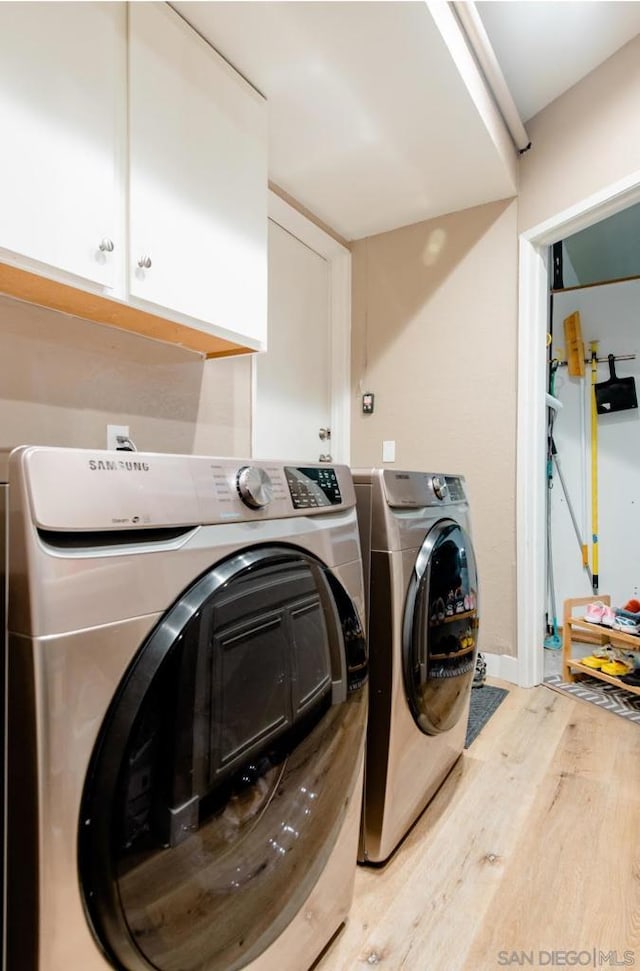 laundry area featuring hardwood / wood-style flooring, cabinets, and washer and dryer