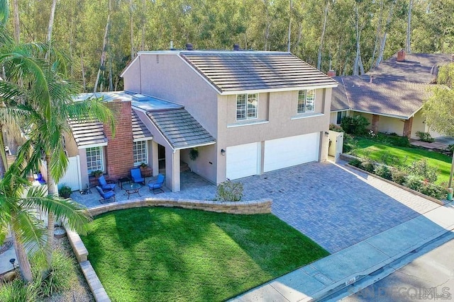 view of front of home featuring a garage, a patio area, and a front lawn