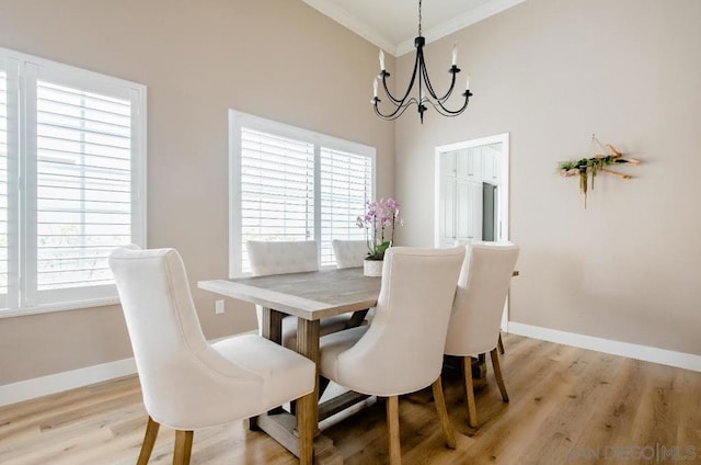 dining area featuring crown molding, a healthy amount of sunlight, a chandelier, and light hardwood / wood-style floors