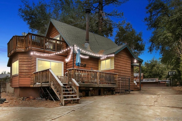 back house at dusk featuring a wooden deck