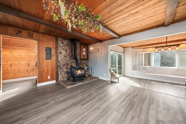 unfurnished living room with wood walls, wooden ceiling, a wood stove, beamed ceiling, and hardwood / wood-style floors