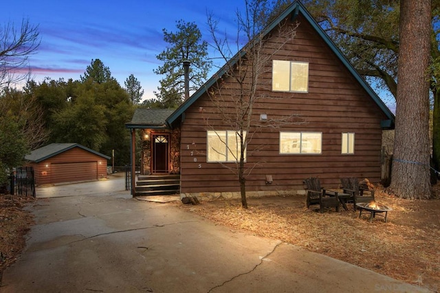 property exterior at dusk featuring a garage and an outbuilding