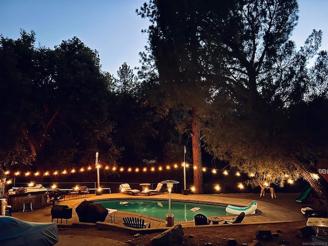 pool at dusk with a patio area