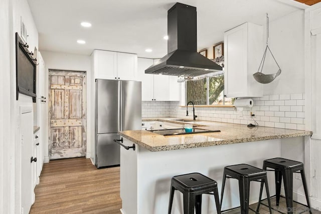 kitchen featuring white cabinetry, stainless steel fridge, kitchen peninsula, and island exhaust hood