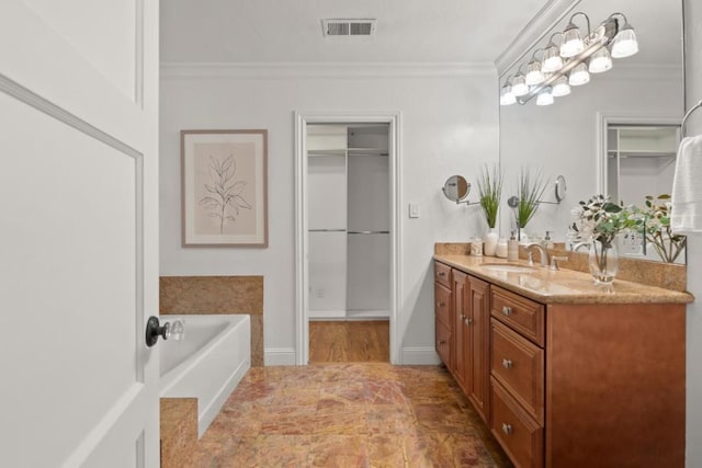 bathroom featuring a tub to relax in, ornamental molding, and vanity