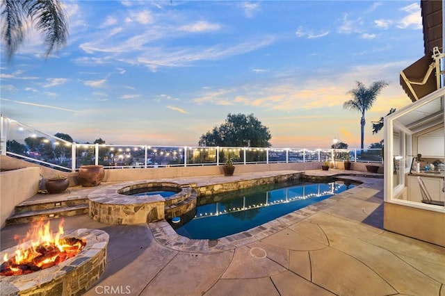 pool at dusk featuring a patio, an in ground hot tub, and an outdoor fire pit