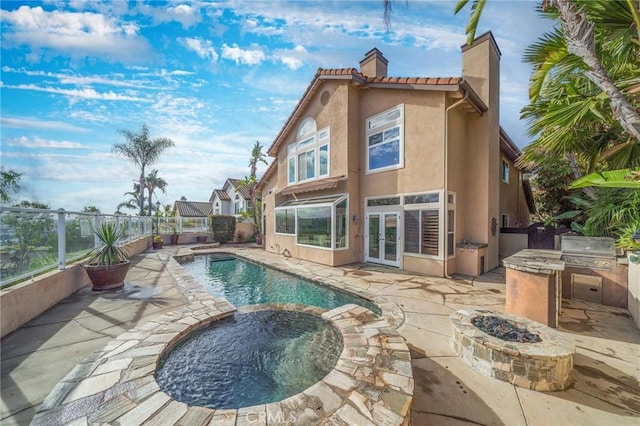 rear view of house with an outdoor fire pit, a patio area, a pool with hot tub, area for grilling, and french doors