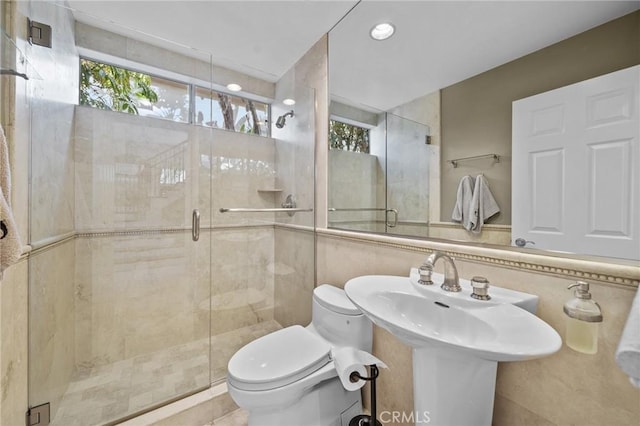 bathroom with tasteful backsplash, toilet, an enclosed shower, and tile walls