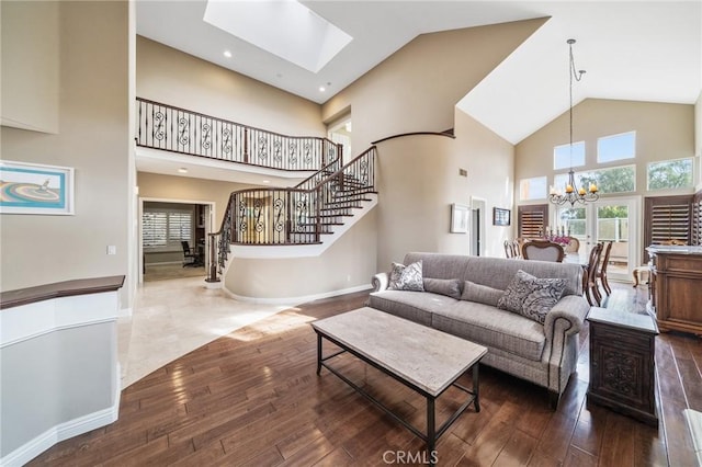 living room featuring a high ceiling, an inviting chandelier, dark hardwood / wood-style flooring, and a skylight