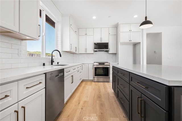 kitchen featuring white cabinetry, stainless steel appliances, decorative light fixtures, and light stone countertops