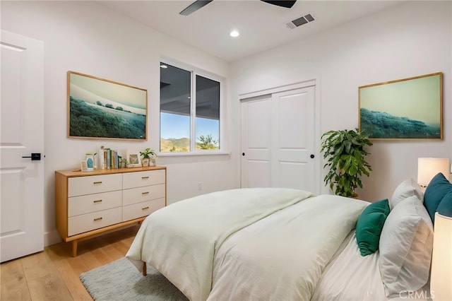 bedroom featuring light hardwood / wood-style flooring, ceiling fan, and a closet