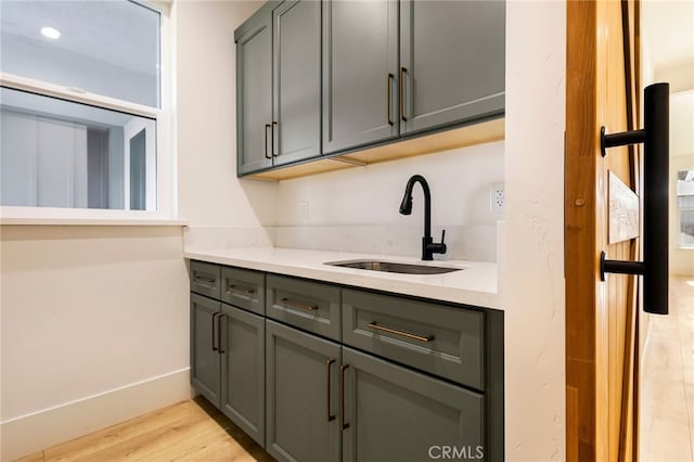 bar with sink, gray cabinets, and light hardwood / wood-style floors