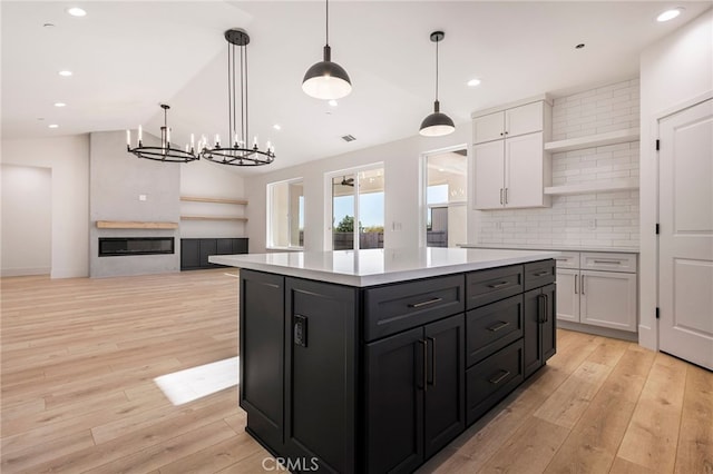 kitchen with white cabinetry, pendant lighting, light hardwood / wood-style flooring, and a center island