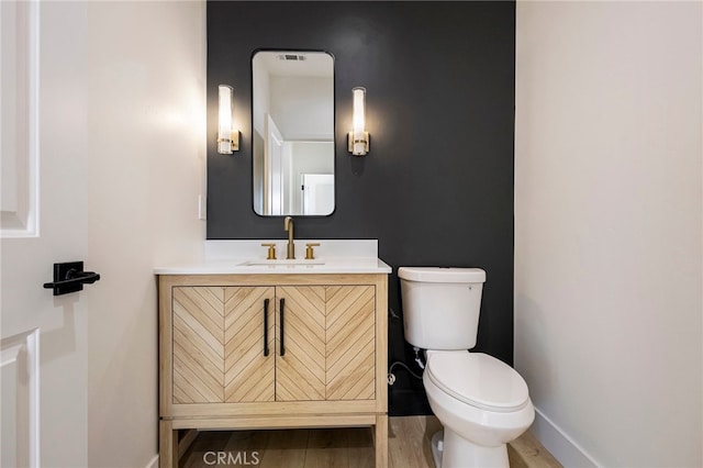 bathroom with hardwood / wood-style flooring, vanity, and toilet