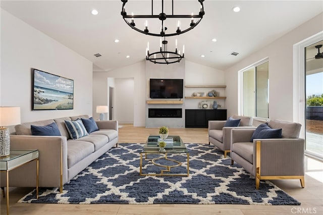 living room with a notable chandelier, vaulted ceiling, and light hardwood / wood-style floors