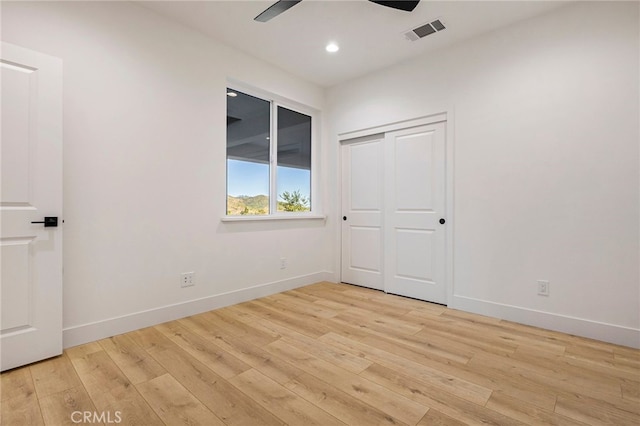 unfurnished bedroom featuring light hardwood / wood-style floors, ceiling fan, and a closet