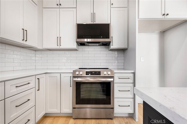 kitchen featuring white cabinetry, light stone counters, tasteful backsplash, light hardwood / wood-style flooring, and stainless steel appliances