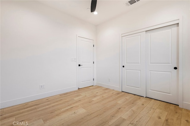 unfurnished bedroom featuring ceiling fan, a closet, and light hardwood / wood-style flooring