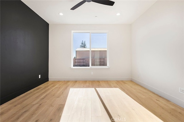 empty room with ceiling fan and light hardwood / wood-style flooring