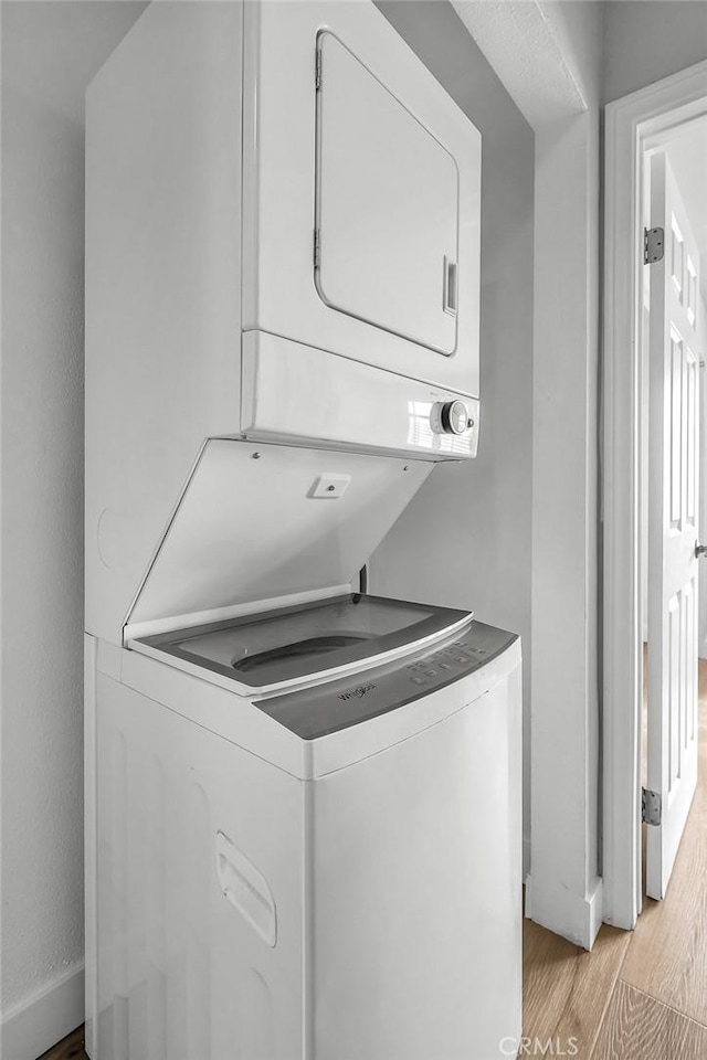 laundry room featuring light hardwood / wood-style floors and stacked washer / drying machine