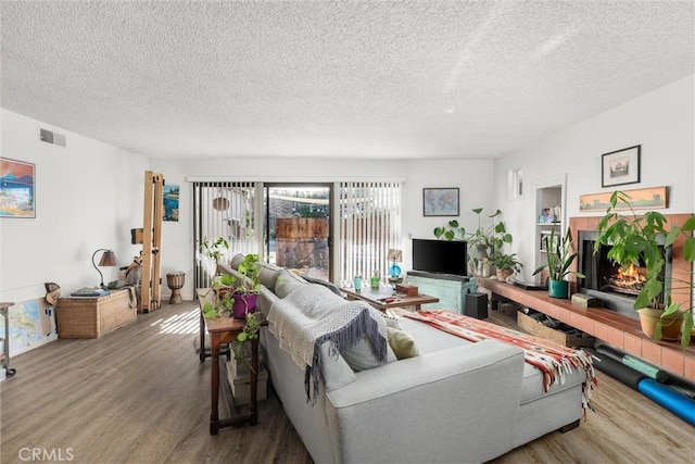 living room featuring a tile fireplace, hardwood / wood-style floors, and a textured ceiling