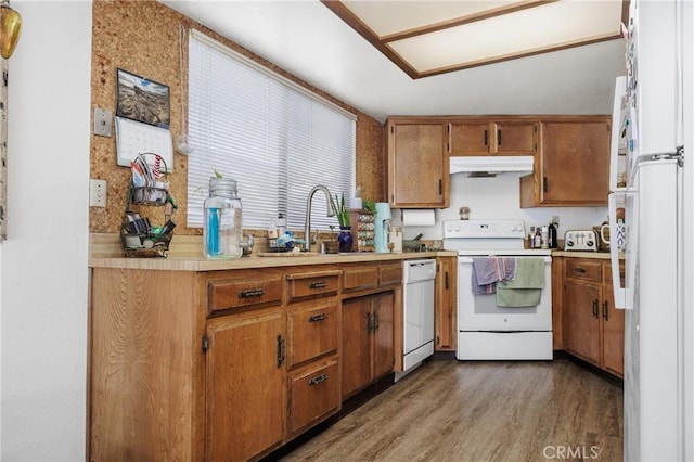 kitchen featuring hardwood / wood-style floors, white appliances, vaulted ceiling, and sink