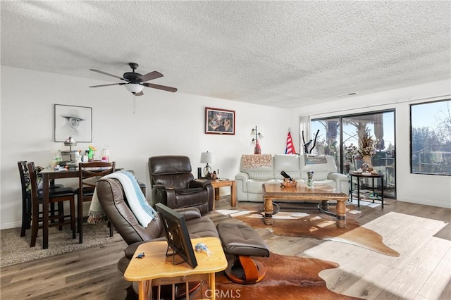 living room with hardwood / wood-style flooring, ceiling fan, and a textured ceiling