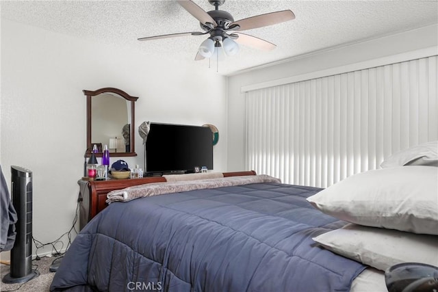 bedroom with ceiling fan, carpet floors, and a textured ceiling