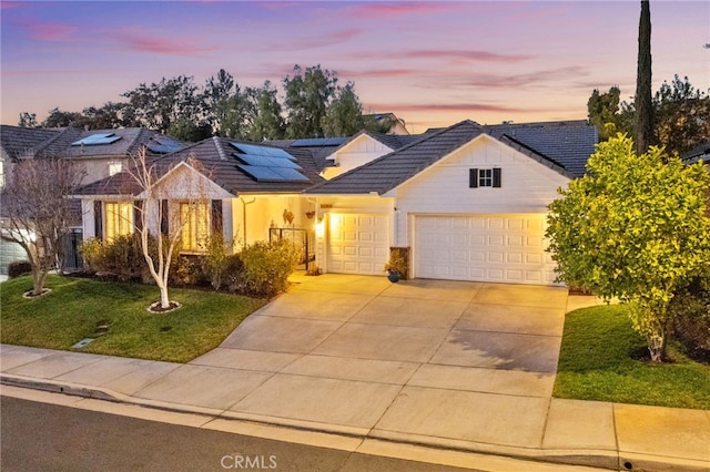 ranch-style house featuring a garage, a lawn, and solar panels