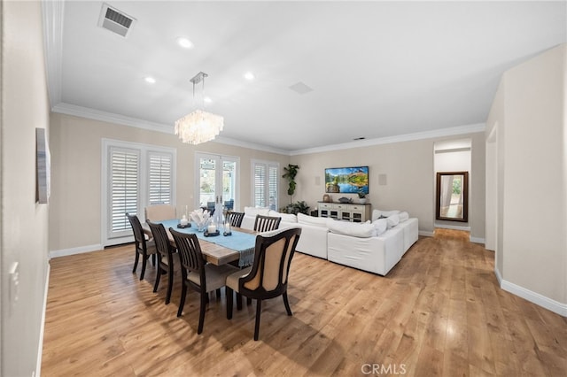 dining room with ornamental molding, an inviting chandelier, and light wood-type flooring