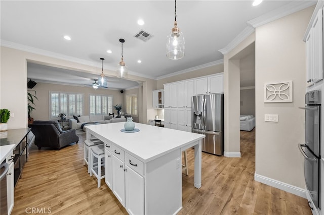 kitchen with a kitchen island, appliances with stainless steel finishes, white cabinetry, a breakfast bar area, and hanging light fixtures