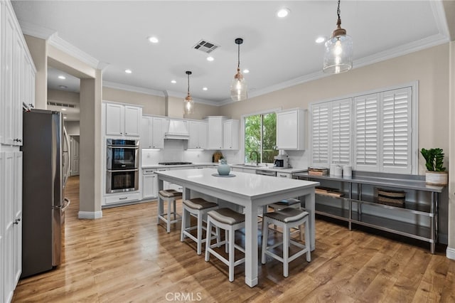 kitchen with a breakfast bar, white cabinetry, a center island, stainless steel appliances, and custom range hood