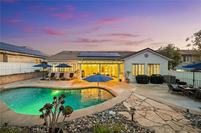 pool at dusk with area for grilling and a patio area