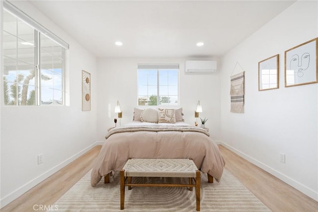 bedroom with a wall mounted air conditioner and light hardwood / wood-style flooring