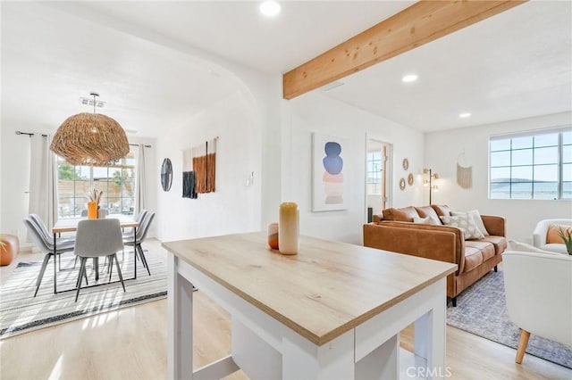 dining area with beam ceiling, a healthy amount of sunlight, and light hardwood / wood-style floors