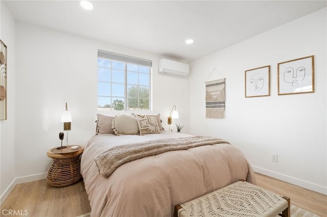 bedroom featuring light hardwood / wood-style flooring and a wall mounted AC