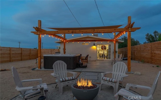 patio terrace at dusk featuring a hot tub and an outdoor fire pit