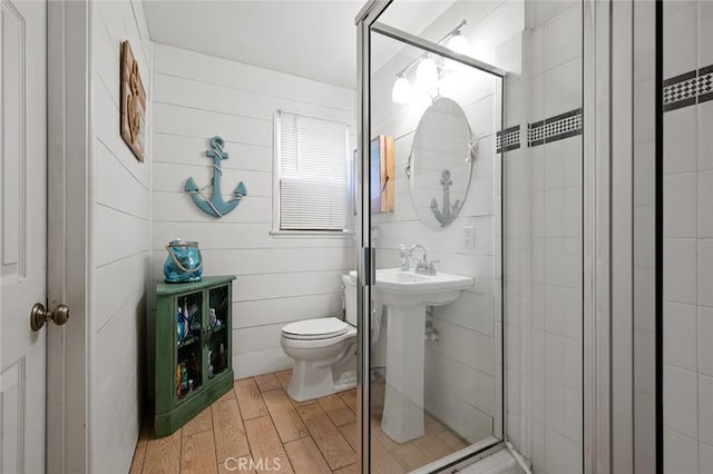 bathroom featuring hardwood / wood-style floors, a shower with door, and toilet