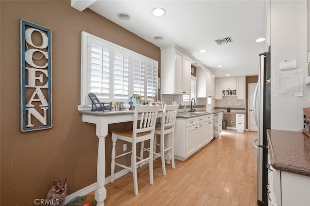 kitchen with white cabinetry, sink, decorative backsplash, and light wood-type flooring