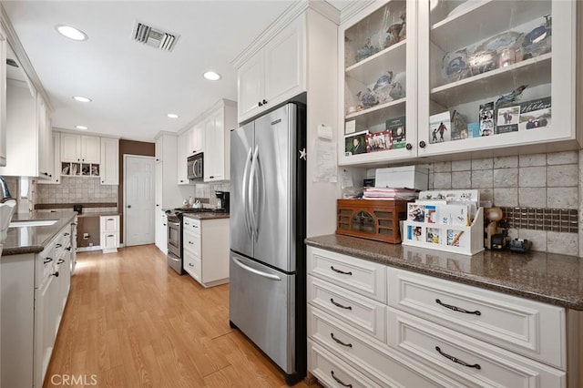 kitchen with sink, backsplash, white cabinets, stainless steel appliances, and light wood-type flooring