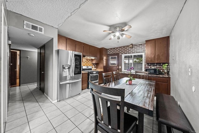 kitchen featuring light tile patterned flooring, ceiling fan, appliances with stainless steel finishes, and tasteful backsplash