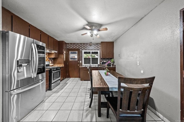 kitchen featuring brick wall, appliances with stainless steel finishes, light tile patterned floors, ceiling fan, and a textured ceiling